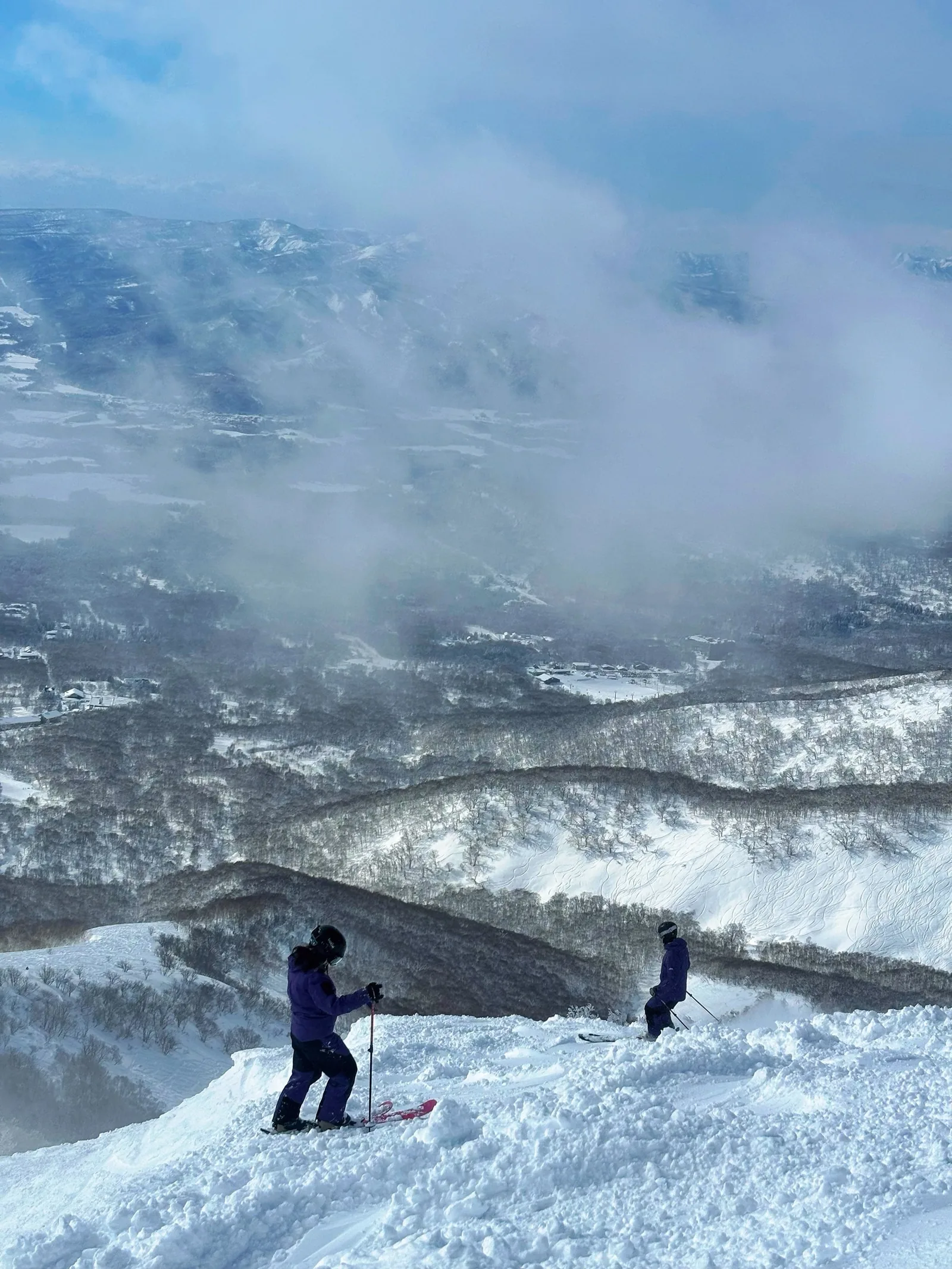 二世谷山頂,兩位滑雪者準備往下滑,背後是雲海與山谷
